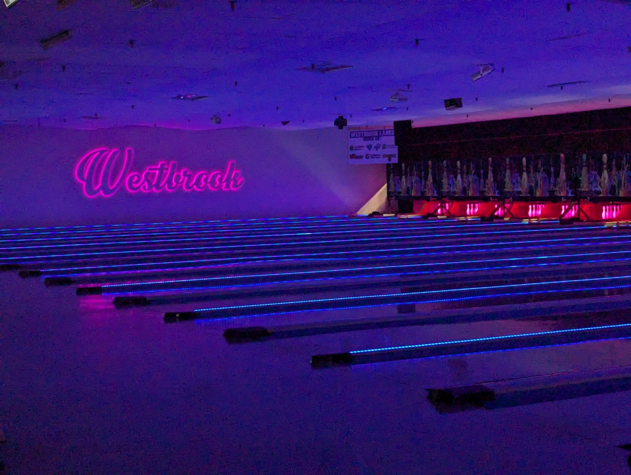 The neon cosmic lanes at Westbrook Lanes — pink Westbrook script sign glowing over blue LED bowling lanes in Brooklawn NJ